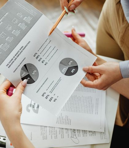 Two people reviewing financial reports and graphs at a desk for analysis and decision-making.